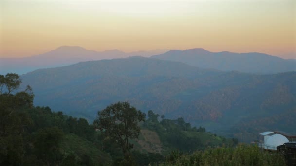 从山脊上俯瞰美丽的景色 日落时俯瞰着一片苍翠的山谷 黄昏时的自然帆布 粉色和群山映衬着地平线的天空 — 图库视频影像