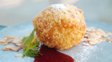 Çilek soslu kızarmış dondurma, badem fıstığı ve beyaz tabakta nane yaprağı. Tropikal bir restoranda servis edilen lezzetli bir tatlı. Yaz tatili için ağız sulandırıcı ikram kavramı. Kapat..