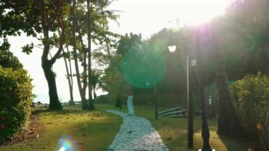 Beyaz elbiseli, şapkalı, plaj tatilinde eğlenen beyaz bir kadın. Phuket 'teki tropik bir spa otelinde mutlu bir gezgin. Yaz seyahati ve tropik cennet kavramı.