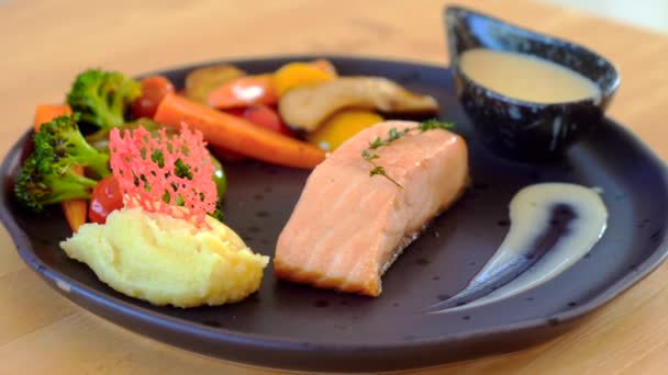 特写美味和健康的鲑鱼牛排与烤土豆 西兰花和胡萝卜 与酱汁放在木制桌子上 午餐或晚餐时的健康营养餐 — 图库视频影像
