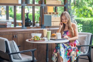 Ahşap kafe masasında karışık yemekler ve huzurlu bir ortam olan bir kadının modern yemek konsepti..