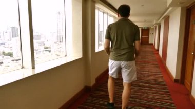 Şehir manzaralı otel koridorunda dans eden bir adam. Kentsel yaşam tarzı ve seyahat.