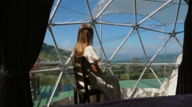 Şeffaf kubbe çadırında oturan, görkemli dağ manzarasına bakan, eşsiz lüks kamp deneyimi, sakin bir kaçış. Seyahat ve eğlence..