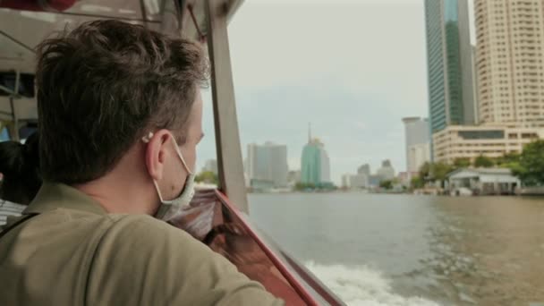 Άνθρωπος Μάσκα Προσώπου Που Απολαμβάνει Τοπίο Της Πόλης Από Πλοίο — Αρχείο Βίντεο
