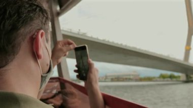 Adam akıllı telefonuyla tekneden manzara fotoğrafı çekiyor. Seyahat ve teknoloji.