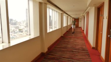 Otel koridorunda şehir manzaralı bir adam yürüyor. Şehir seyahati ve konaklama.