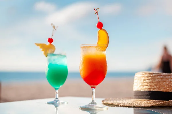 Tropical cocktails on beach table with sea in background. Summer vacation.