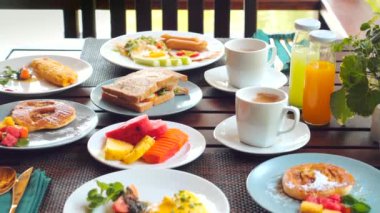 Sabahları çeşitli meyve, ekmek, krep ve içeceklerin yer aldığı masalara serpilmiş taze ve renkli bir kahvaltı. Besleyici bir sabah yemeği..
