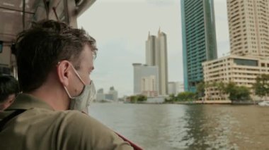 Man wearing face mask while commuting by boat in city. Urban transportation during pandemic.