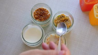 Bir insan dört kavanoz malzemenin önünde bir kaşık tutuyor, yeni bir yemek tarifi için farklı gıda katkı maddeleri ve sıvılarla aşçılık deneylerini sergiliyor..