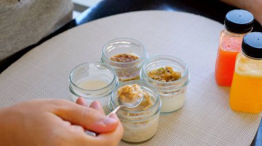 Bir insan dört kavanoz malzemenin önünde bir kaşık tutuyor, yeni bir yemek tarifi için farklı gıda katkı maddeleri ve sıvılarla aşçılık deneylerini sergiliyor..