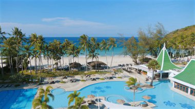 Tropik plaj tatil beldesi palmiye ağaçları, yüzme havuzları ve tatil için okyanus manzaralı panoramik manzara. Egzotik eğlence ve eğlence mekanı.