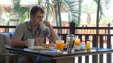 Adam açık hava restoranında çırpılmış yumurta, meyve ve meyve suyu ile dengeli kahvaltıyı seviyor. Taze yemekle beslenme ve sağIık..