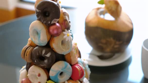 美味的甜甜圈金字塔放在酒店的桌子上 男人吃新鲜多彩的甜甜圈 甜蜜的放纵 — 图库视频影像