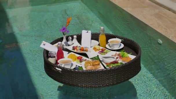 热带旅游胜地的异国情调游泳池里 丰盛的漂浮早餐 有新鲜水果 饮料和鲜花的丰盛的晚餐放在编织好的盘子里 体验高档旅游及膳食 — 图库视频影像
