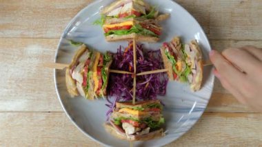 Sağlıklı kulüp sandviçleri ızgara tavuk, peynir ve yanında rendelenmiş mor lahana ve ahşap masa ile servis edilen taze sebzeler. Gurme ve besleyici yemek.