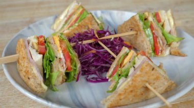 Çıtır marul ve olgun domateslerle servis edilen taze hazırlanmış tavuk kulübü sandviçi yanında da seramik tabakta mor lahana salatası. Sağlıklı yemek ve yaşam tarzı.