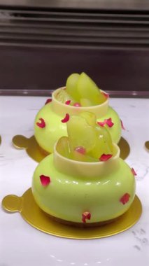 Altın bardak altlıklarında sunulan yeşil jöleli ve şeffaf dilimli zarif hamur tatlısı gurme tatlılığını ve güzel yemekleri sembolize ediyor. Nefis şekerlemeler ve pastaneler..