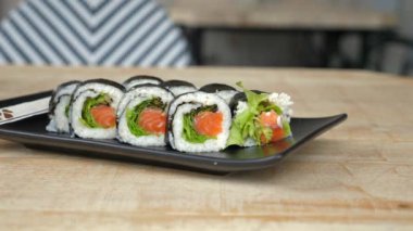 Modern tabakta zencefil turşusu ve wasabi ile servis edilen taze somon suşi ruloları, gastronomi meraklıları için Japon mutfağı sunumu. Gurme Asya yemekleri ve yemekleri.