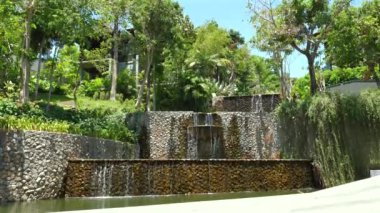 Lüks villa mimarisi ile harmanlanmış taştan şelaleleri olan verimli tropikal bir bahçe. Huzurlu manzarada çevre dostu ve sürdürülebilir tasarım.