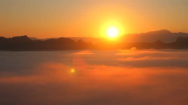 Sabahın erken saatlerinde sisli dağ manzarasını aydınlatan altın ışıkla huzurlu bir gün doğumu. Yumuşak sis vadileri ile güzel bir ufuk manzarası. Doğanın sükunetini ve güzelliğini yakalıyor..