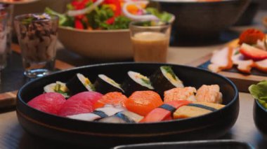 Masada taze malzemelerle karışık suşi tabağı, yanında salatalar ve soslar, Asya mutfağı ve gurme yemekleri için mükemmel. Japon Yemek ve Mutfak Sanatları