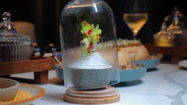 Zarif yemeklerden oluşan bir gurme sofrası, mermer masaya güzelce döşenmiş, arka planda bir bardak beyaz şarap var. Güzel Yemek ve Mutfak Sanatı.