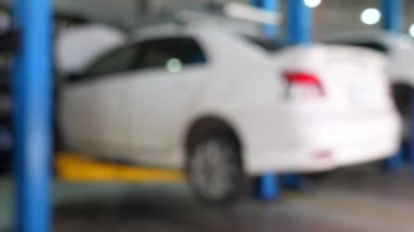 Araba tamirhanesinde asansördeki beyaz arabanın bulanık görüntüsü, araç bakım ve onarım hizmetlerinin altını çizmek. Otomobil Hizmeti ve Bakımı.