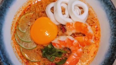 Bir kase lezzetli baharatlı deniz mahsulü ramen, karides, kalamar halkası, yumurta sarısı, limon dilimleri ve taze soğan Asya mutfağının ve yemeğin mükemmel bir temsili. Asya Mutfak ve Yemekleri.