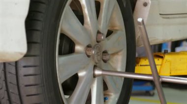 Tamirci araba tamirhanesinde fındıkları sıkılaştırmak için ingiliz anahtarı kullanıyor, yakın plan, araç bakımına ve mekanik işe odaklanıyor. Otomotiv Tamir ve Bakım.