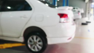 Parlak ışıklandırılmış otomobil tamirhanesindeki arabaların bulanık görüntüsü, araba ve mekanik alana odaklanma, otomotiv ve araç bakımını yansıtan görüntüler. Otomatik Onarım ve Bakım