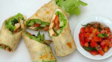 Taze sebze ve tavuk sargıları yanında doğranmış domates ve yeşilliklerle birlikte beyaz arka planda..