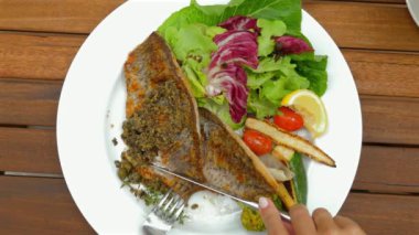 Karışık sebzeli ızgara balık, kiraz domatesleri, bebek mısır ve beyaz tabakta limon dilimi, ahşap masa. Renkli sebzeli sağlıklı gurme yemeği..