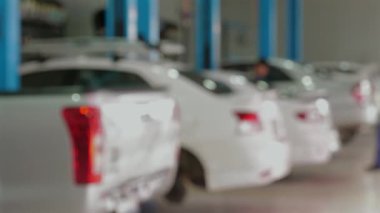 Garajda park etmiş bir sürü beyaz arabası olan, arka planda yürüyen bir tamirci olan işlek otomobil tamircisinin bulanık görüntüsü. Otomotiv Bakım ve Onarım.