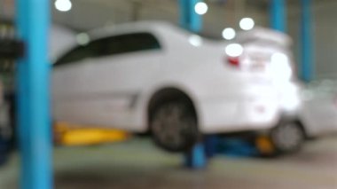 Oto tamirhanesinde servis edilen beyaz arabanın bulanık görüntüsü. Otomobil bakım ve onarımı.