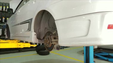 Araba oto tamirhanesinde hidrolik asansörde, fren ve lastik tamiri yapılıyor. Otomotiv onarımı ve bakımı.