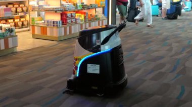 Modern havaalanı terminalinde otonom temizlik robotu yerleri süpürüyor, kamusal alanlarda otomatik teknolojinin geleceğini temsil ediyor. Yenilik ve Otomasyon. Phuket Havaalanı, Tayland, 23 Şubat 2024