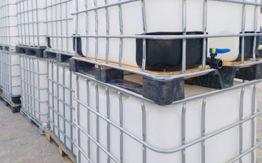 Bir sürü küp su tankı. Dışarıya yığılmış 1000 litre konteynır.