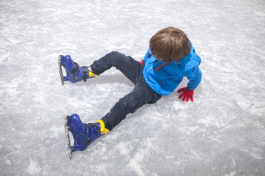 Child boy after suffering a fall on the ice rink. Temporary skating installation