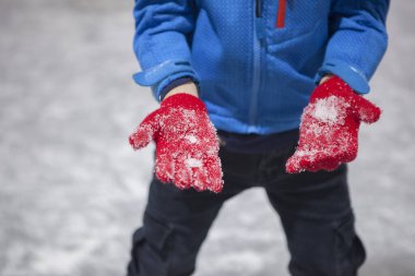 Child boy show his gloves full of ice. Recreational ice rink concept