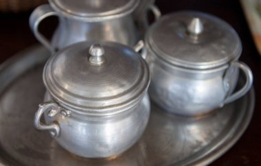 Old aluminum sugar bowls on a tray. Selective focus