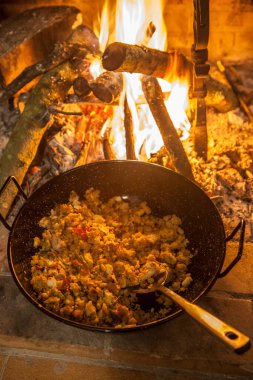 Spanish migas casserole being cooked at fireplace. Selective focus