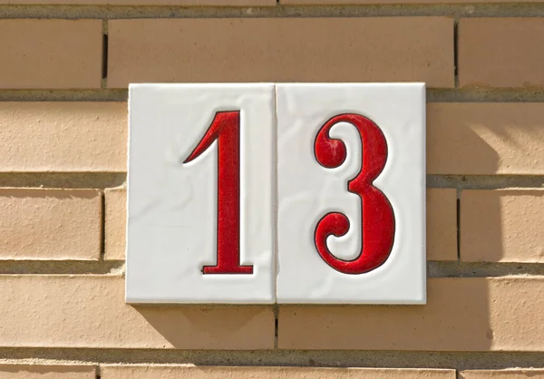 House number 13 over brick sunny wall. Houses with personality concept