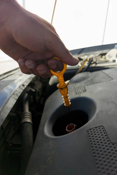 男は古いディーゼルエンジンから自分の油レベルをチェックします ガソリンスタンドの背景 — ストック写真