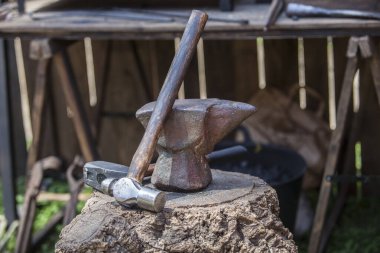 Örs, çekiç ve topuz mantar meşe kütüğünün üzerinde sergileniyor. Eski bir Roma askeri kampından demirci aletleri.. 