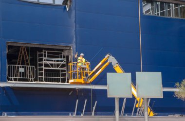 İşçi inşaat halindeki bir binaya yalıtım panelleri yerleştiriyor. Tele-el vinci aştı.