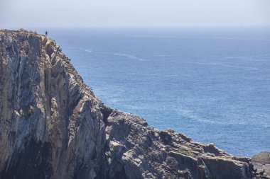 Cabo Sardao sahilinin tepesinden denizi izleyen ziyaretçi, Ponta do Cavaleiro, Sao Teotonio, Portekiz