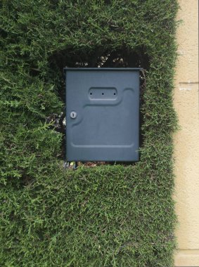 Kalın bir çitle gömülü dış posta kutusu. Yurt içi bahçe kavramı