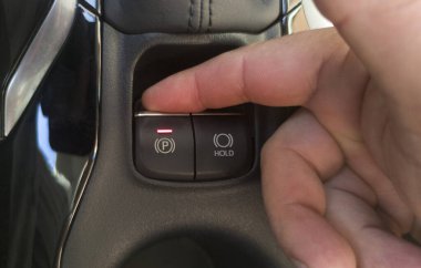 Sürücü arabasının elektrikli park frenini çalıştırıyor. Düğmeye seçici odaklanma