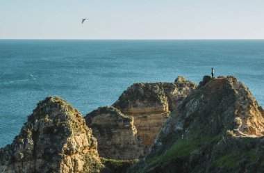 Ponta da Piedade, Lagos, Algarve bölgesi, Portekiz 'in tepesinden denizi izleyen bir turist.